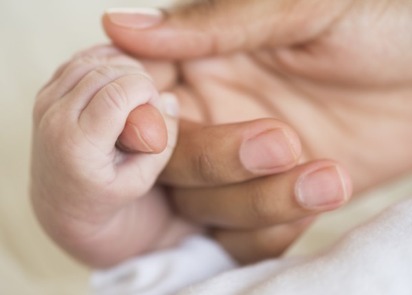 Hispanic mother holding infant's hand