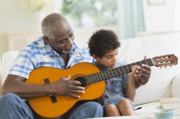 Boy playing guitar with grandfather