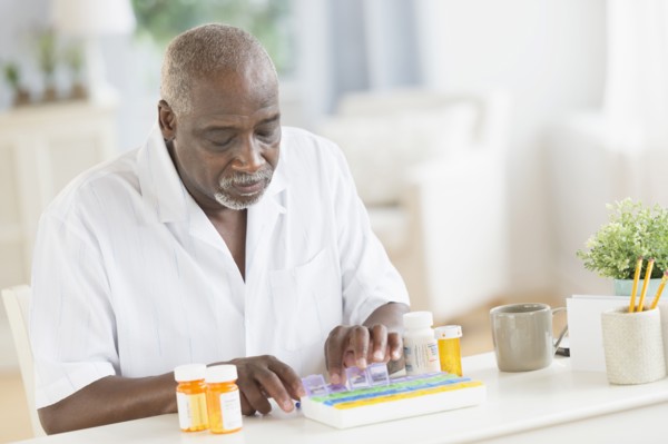 Black man counting pills in pill boxes