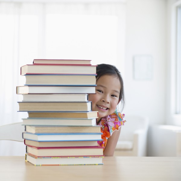 Korean girl peeking from behind stack of books