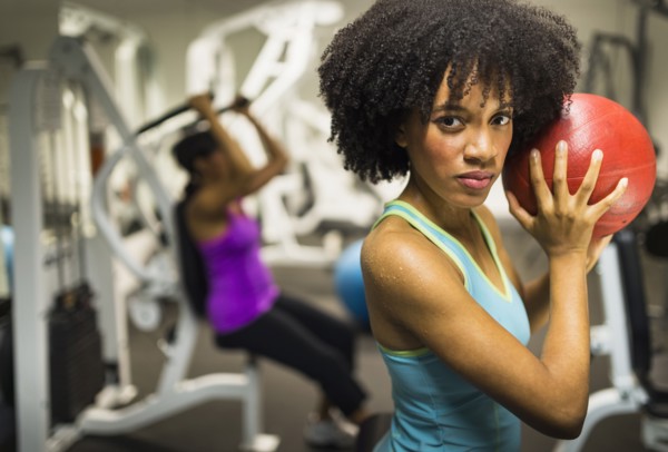 African American woman holding medicine ball in gym