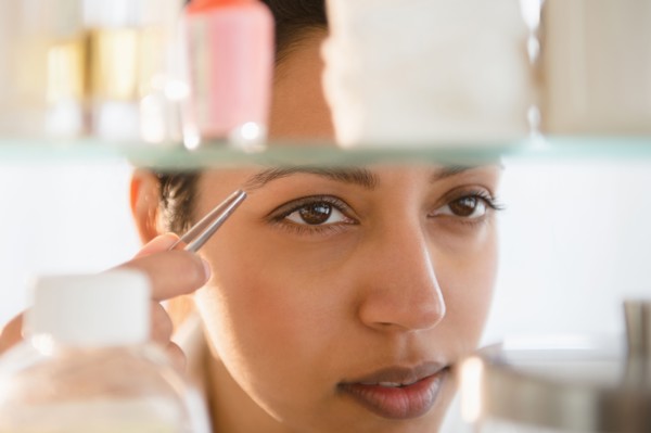 Close up of Asian woman tweezing eyebrows