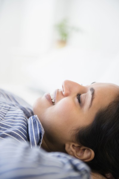 Close up of serene Asian woman laying with hands behind head