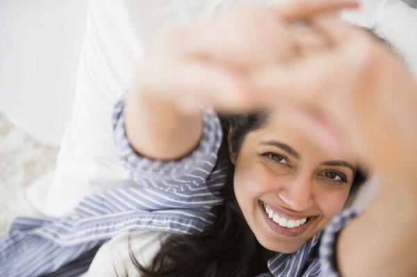 Close up portrait of smiling Asian woman laying in bed