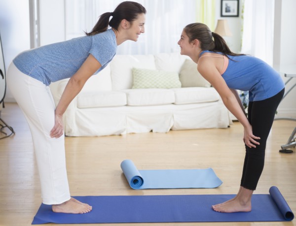 Caucasian mother and daughter practicing yoga in living room