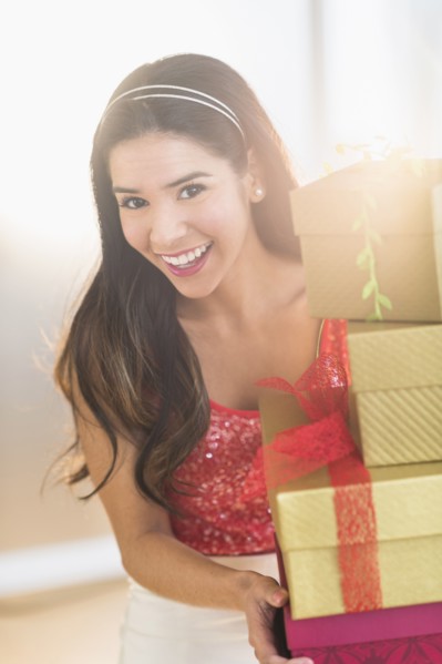 Portrait of smiling Hispanic woman carrying Christmas gifts