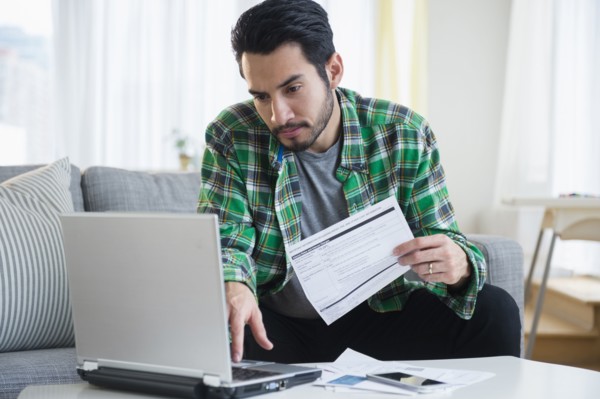 Mixed race man paying bills in living room