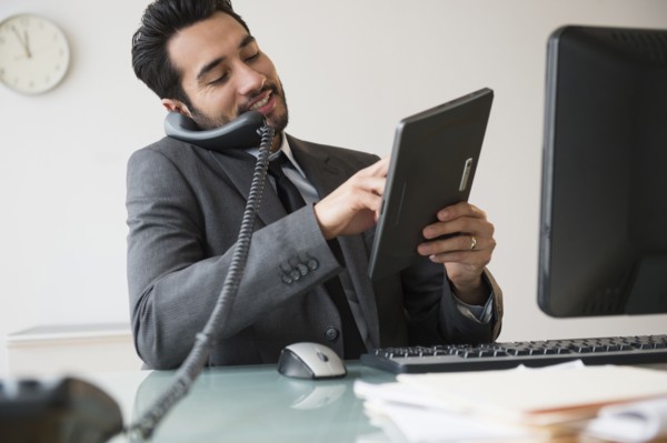 Mixed race businessman using digital tablet on telephone