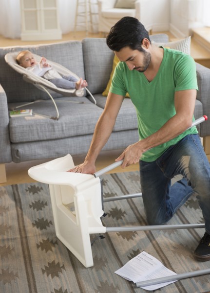 Father setting up highchair in living room