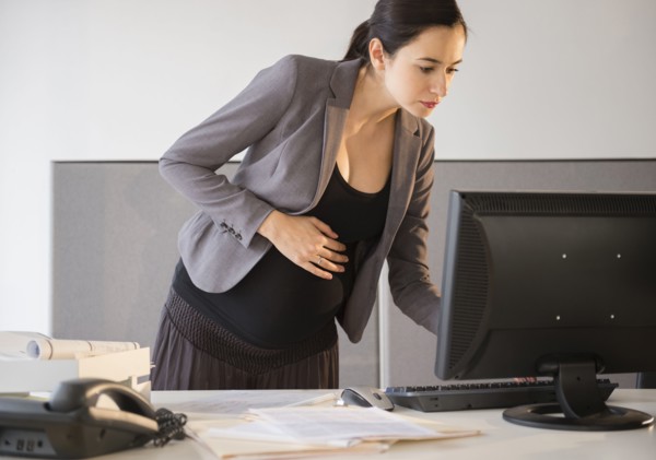 Pregnant Caucasian businesswoman working in office