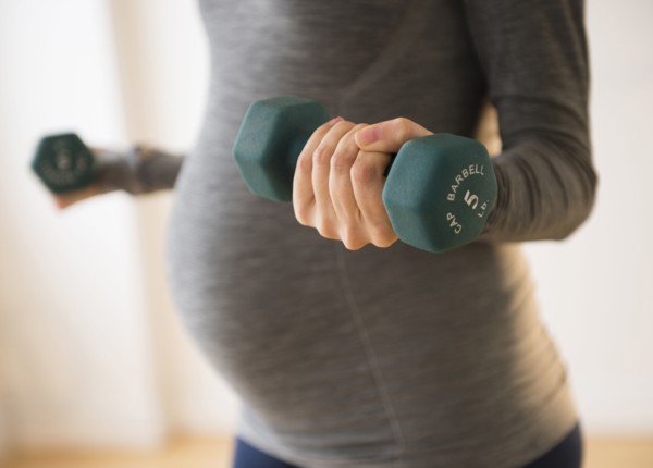 Pregnant Caucasian woman lifting weights