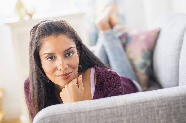 Hispanic woman laying on sofa