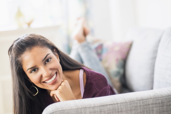 Hispanic woman laying on sofa