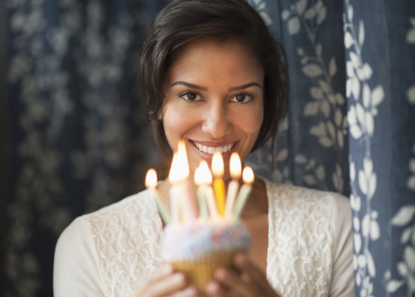 Hispanic woman holding birthday cupcake