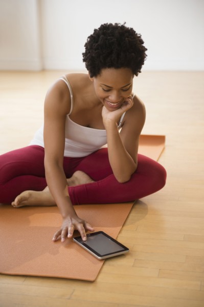 Black woman using digital tablet on yoga mat