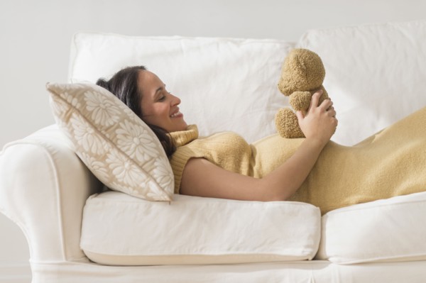 Pregnant Hispanic woman admiring teddy bear