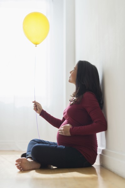 Pregnant Hispanic woman holding balloon