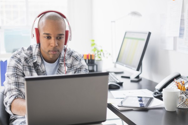 Black businessman listening to headphones in office
