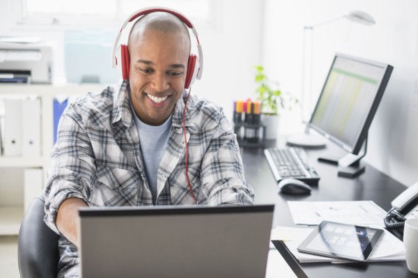 Black businessman listening to headphones in office