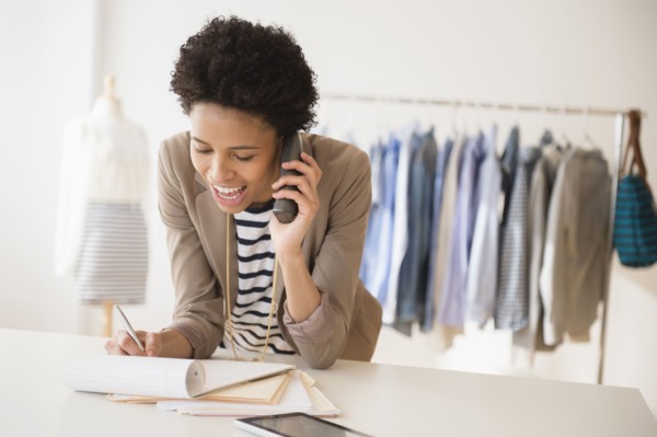Black dressmaker talking on phone in studio