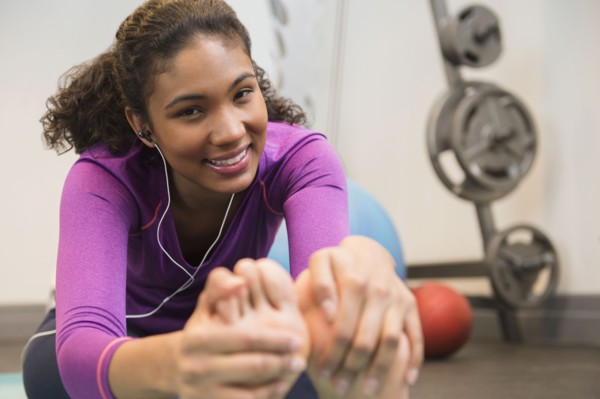 Mixed race woman stretching in gym