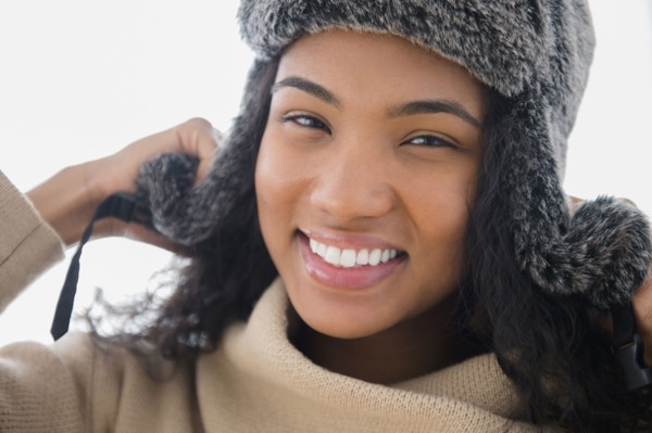 Mixed race woman wearing furry hat in snow