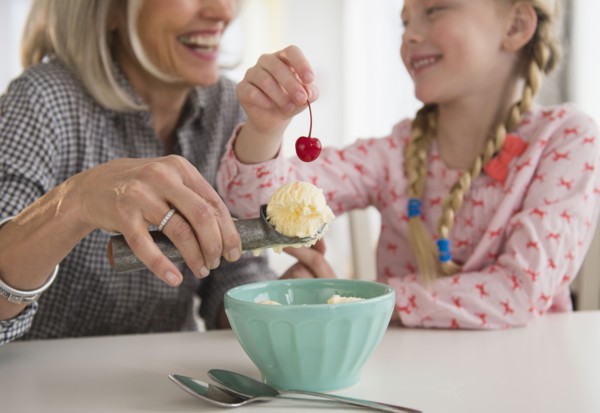 Senior Caucasian woman and granddaughter making ice cream sundae