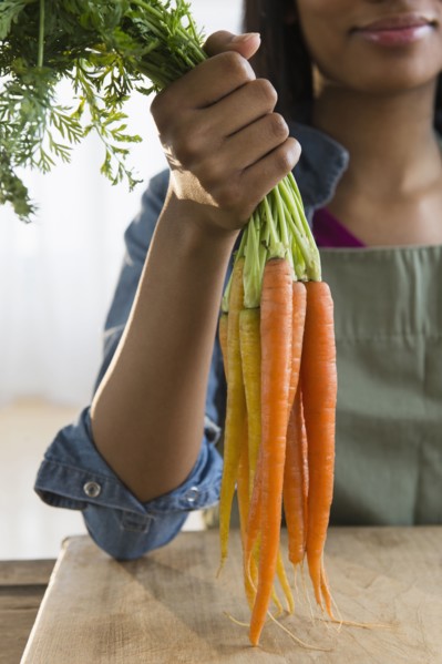 Mixed race woman holding bunch of carrots