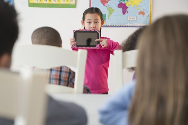 Girl showing digital tablet to classroom