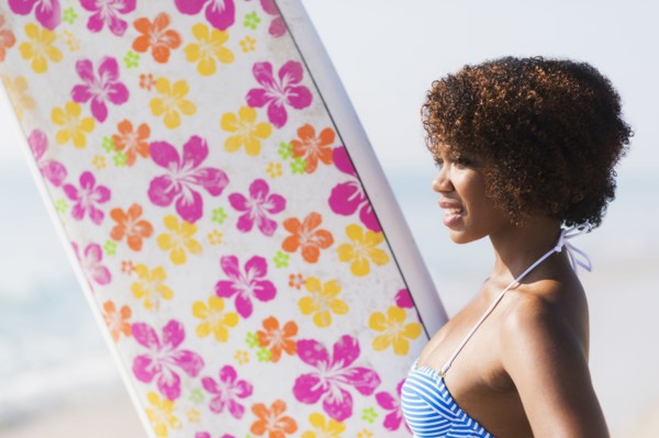 Woman carrying surfboard on beach