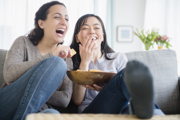 Women laughing on sofa together