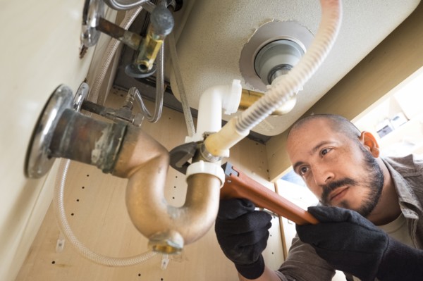 Hispanic plumber working under sink