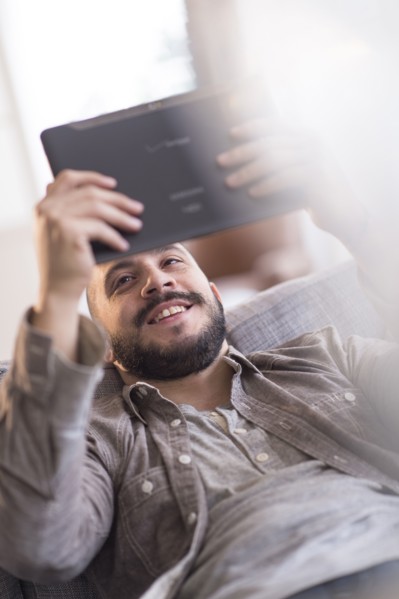 Hispanic man using digital tablet on sofa
