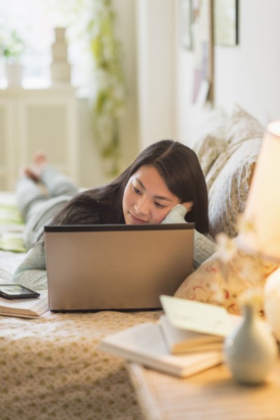 Mixed race teenage girl doing homework on bed