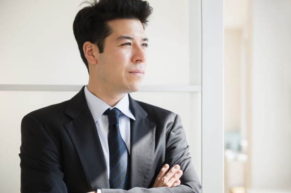 Mixed race businessman standing at window