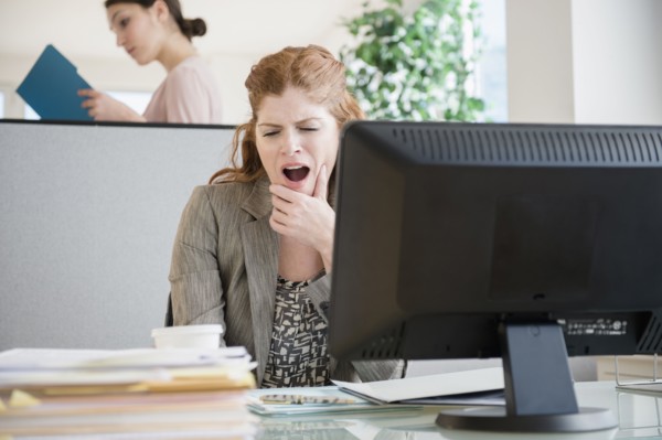 Caucasian businesswoman yawning at desk