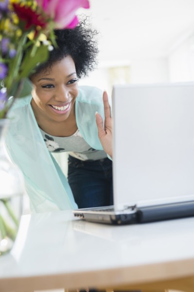 African American woman video chatting with laptop