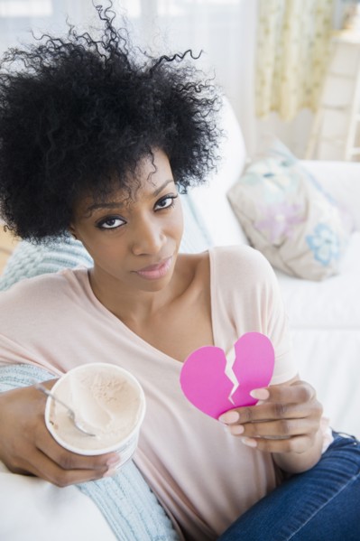 African American woman holding broken heart and ice cream