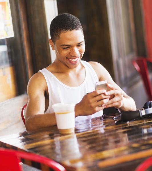 African American man using cell phone at cafe