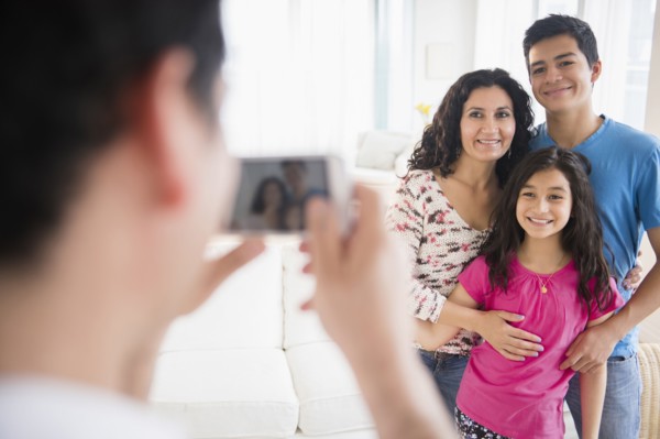 Hispanic family taking cell phone photograph in living room