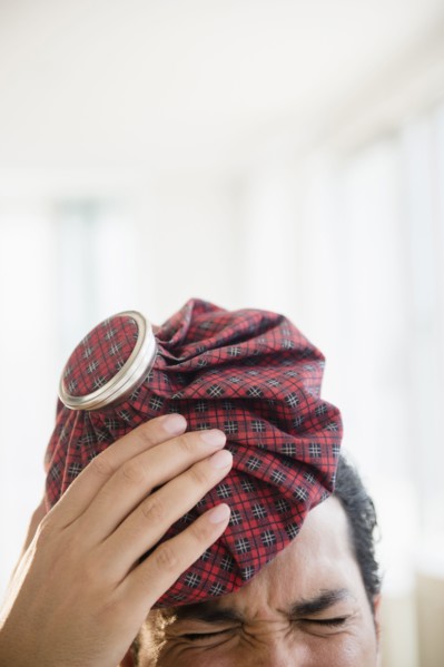 Mixed race man holding ice pack to head