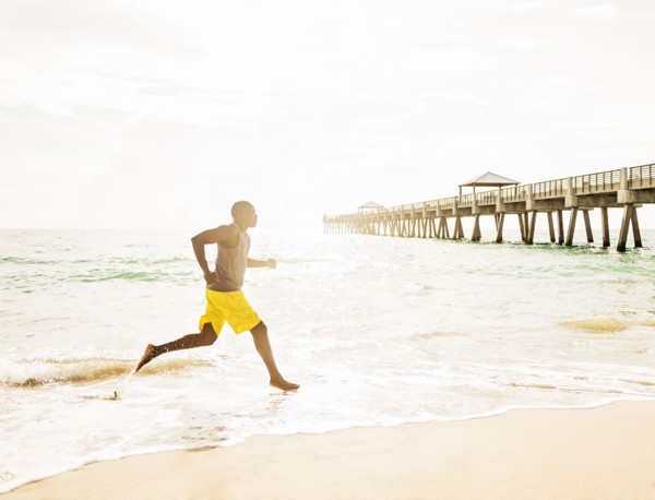Mixed race barefoot man running on beach