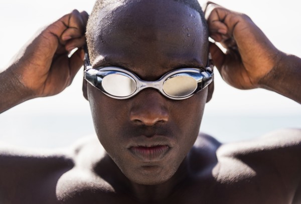 Mixed race swimmer putting on goggles