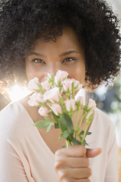 Woman smelling bouquet of roses indoors