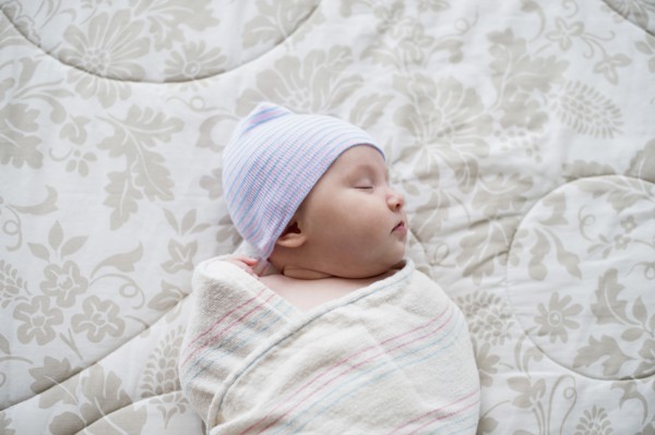 Swaddled Asian baby sleeping on bed