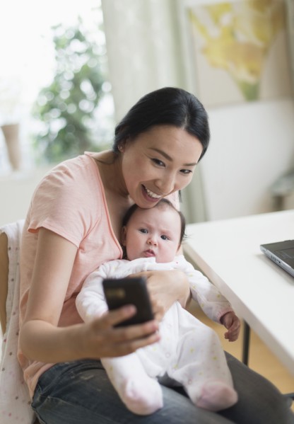 Asian mother and baby taking selfie in home office