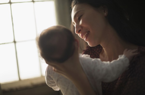Asian mother holding baby near window