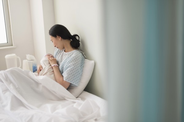 Asian mother holding newborn baby in hospital