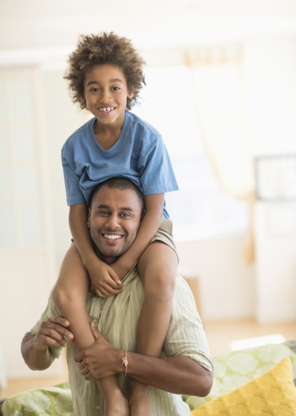 Father carrying son on shoulders in living room
