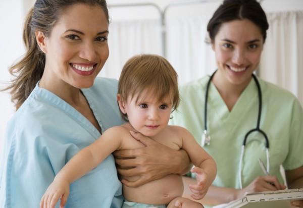 Pediatrician doctor and nurse holding baby girl in hospital